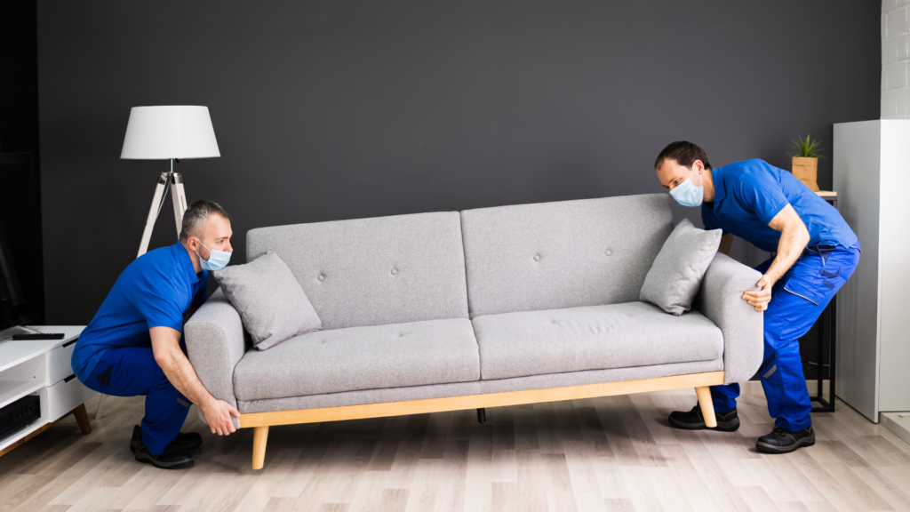 a picture of 2 professional movers moving a couch