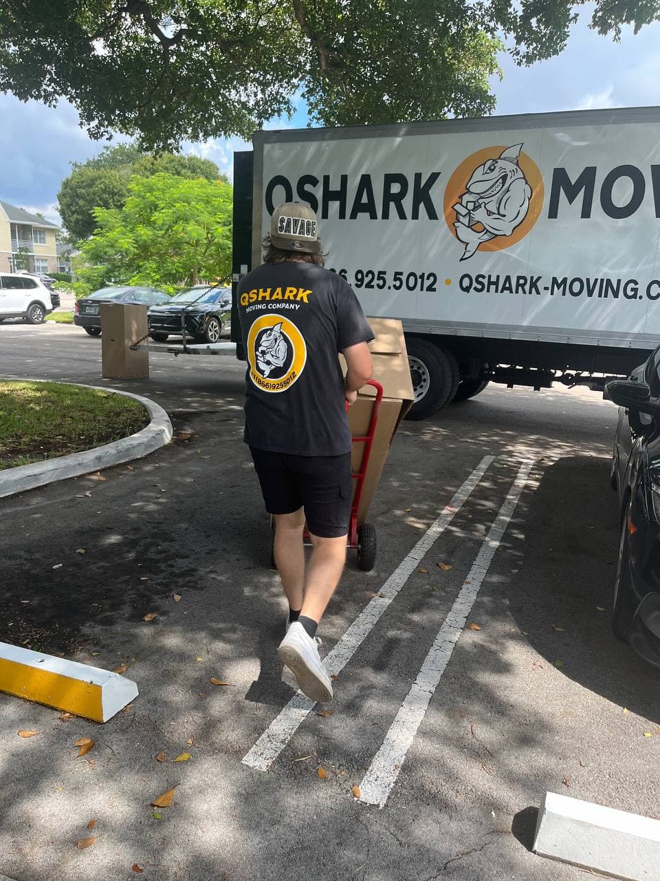 Qshark mover carrying boxes near moving truck in Miami