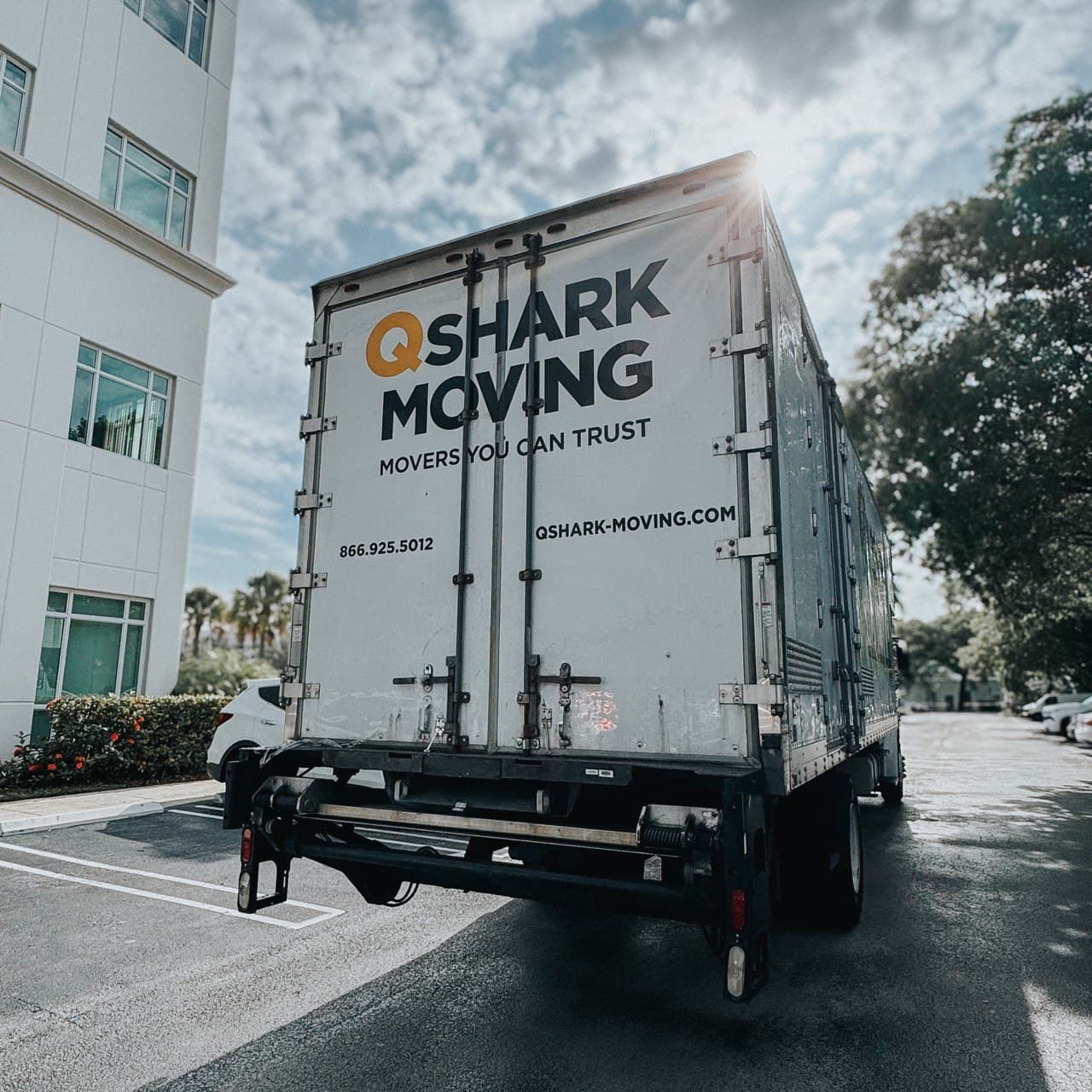 Qshark Moving Company branded truck parked near office