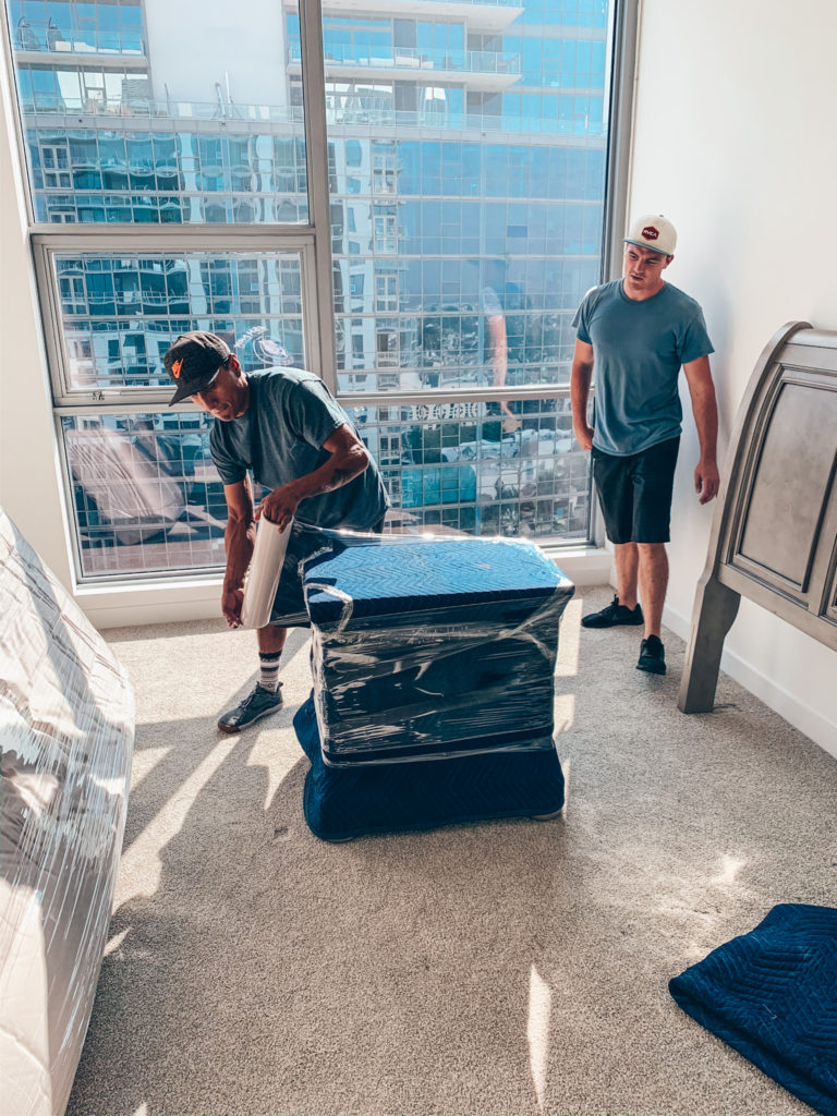 Two movers wrapping a nighstand before a local move. 