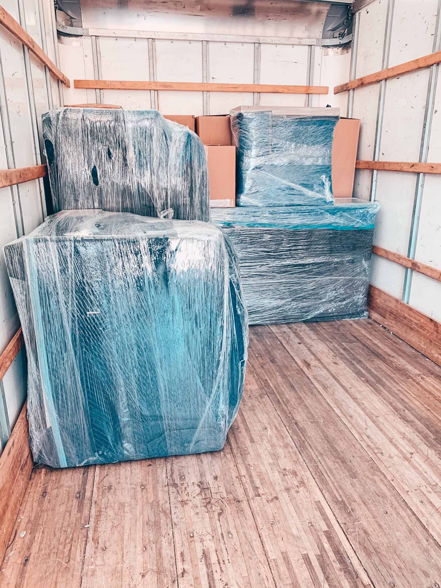 Furniture covered with plastic wrap and moving blankets