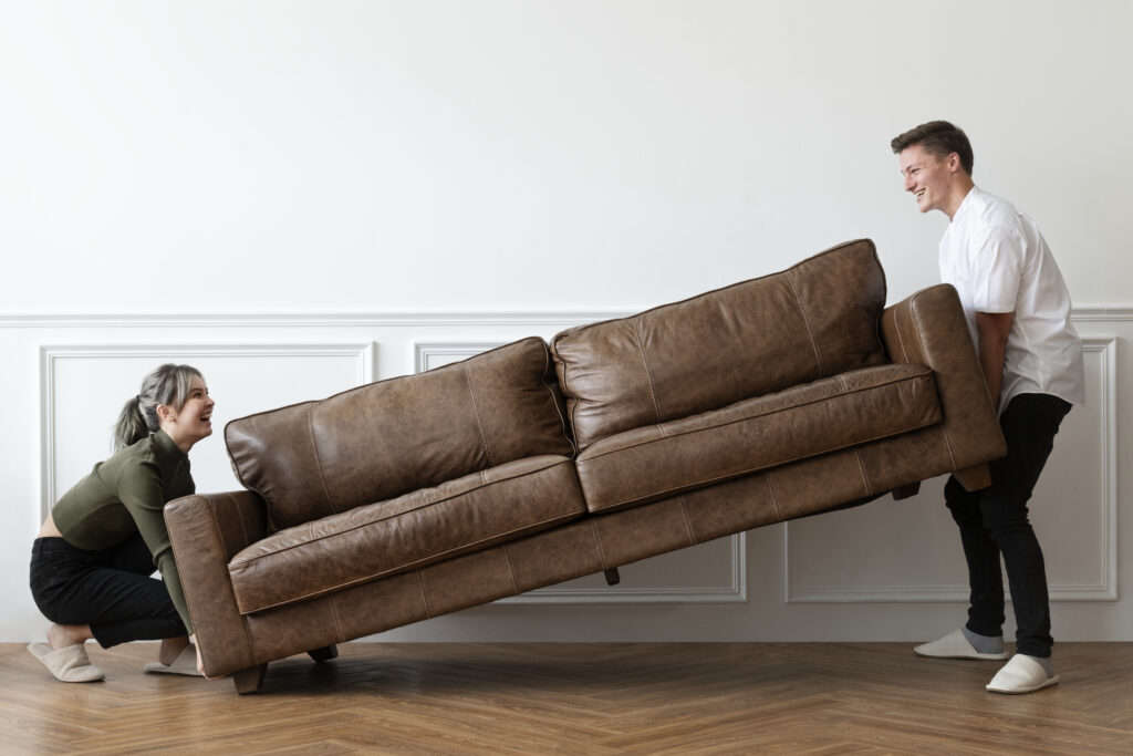 Couple carrying a couch together while following expert tips on how to load a moving truck for an efficient and stress-free move.