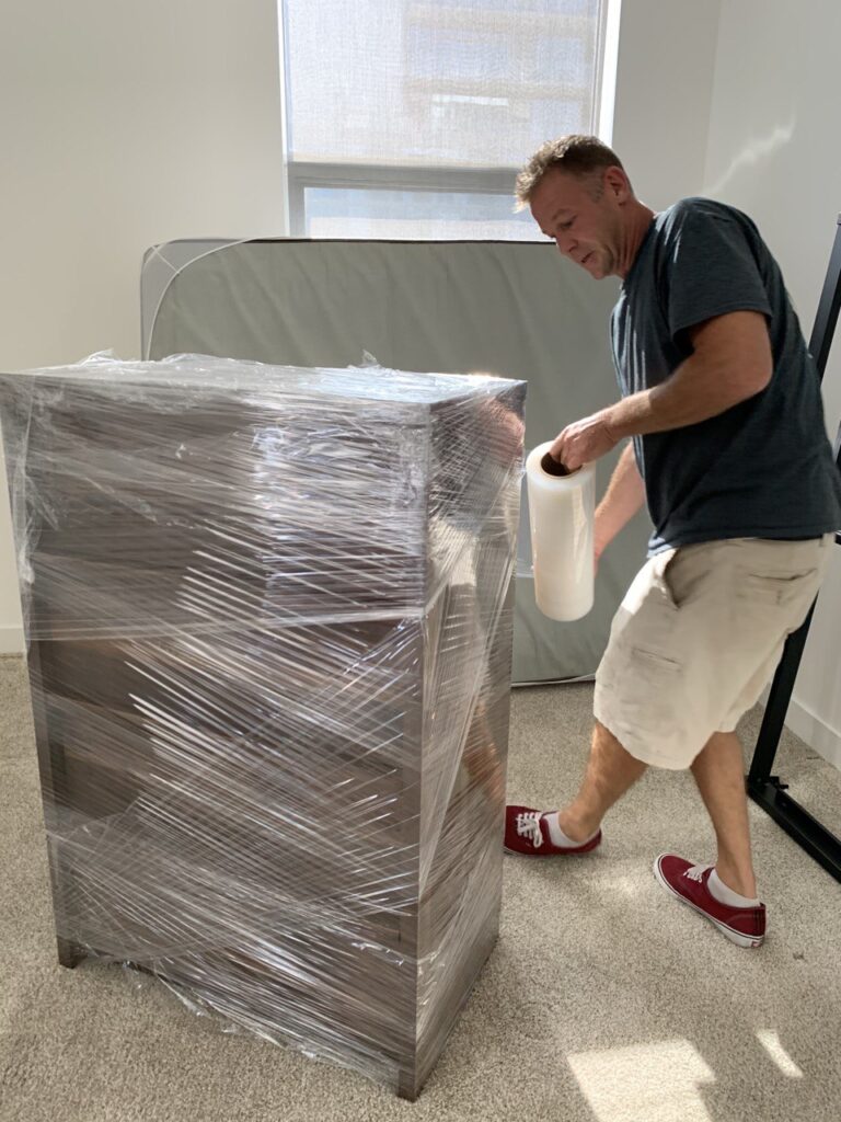 A mover wrapping a dresser before moving