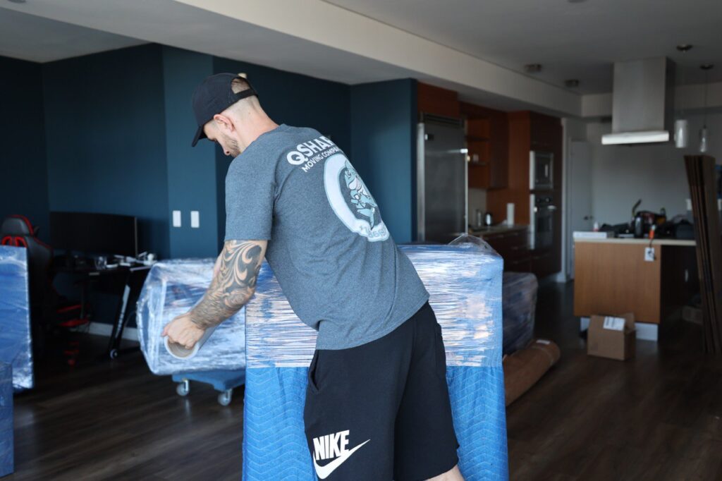 a picture of a movers wrapping a dresser