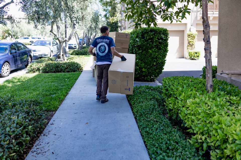 a picture of qshark mover carrying the boxes to customers house 