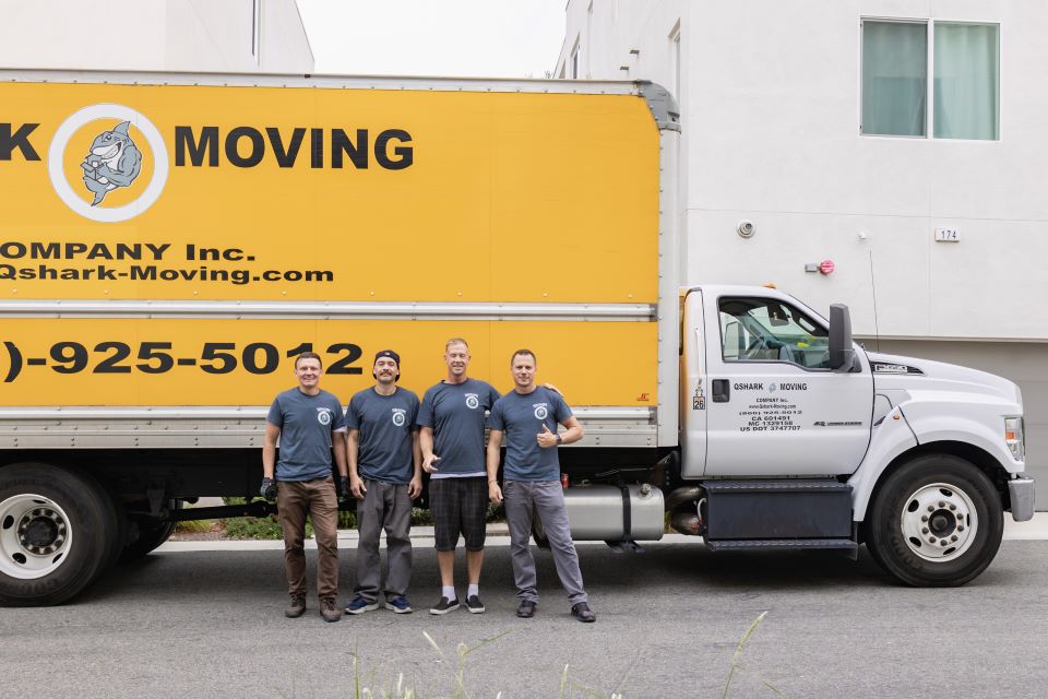 a picture of qshark movers standing next to a moving truck