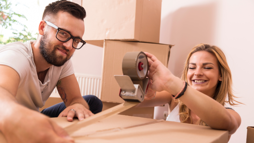 a couple sealing a box for moving